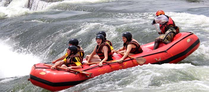 Tourists go over a rapid on the Nile river while water rafing