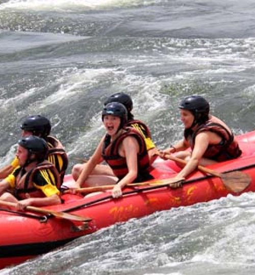 Tourists go over a rapid on the Nile river while water rafing
